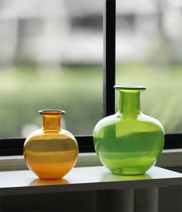 Glossy Coloured Glass Bottle Vases in Amber and Grass Green — in a room setting