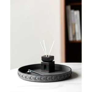 Round Black Leather Entryway Tray with Studded Rim in black — in a room setting