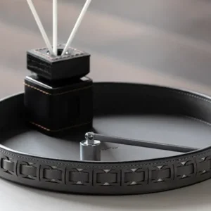 Round Black Leather Entryway Tray with Studded Rim in black — in a room setting