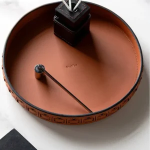 Round Black Leather Entryway Tray with Studded Rim in black — in a room setting
