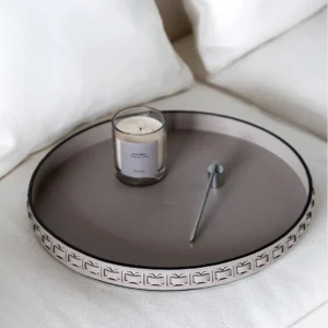Round Black Leather Entryway Tray with Studded Rim in black — in a room setting