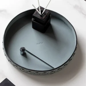 Round Black Leather Entryway Tray with Studded Rim in black — in a room setting