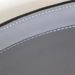 Round Black Leather Entryway Tray with Studded Rim in black — in a room setting
