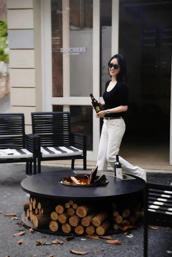 Round Outdoor Wood-Burning Fire Pit in black — in a room setting