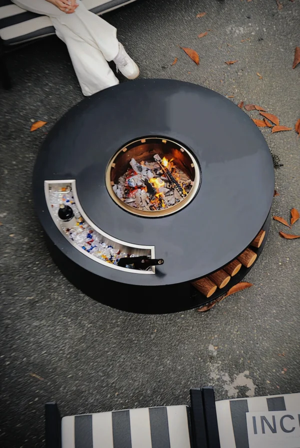Round Outdoor Wood-Burning Fire Pit in black — in a room setting