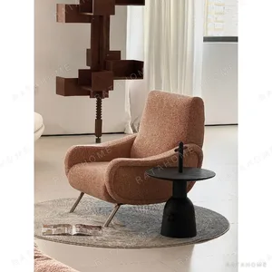 Curved Blush Fabric Lounge Chair on Slim Metal Legs in rose stone — in a room setting