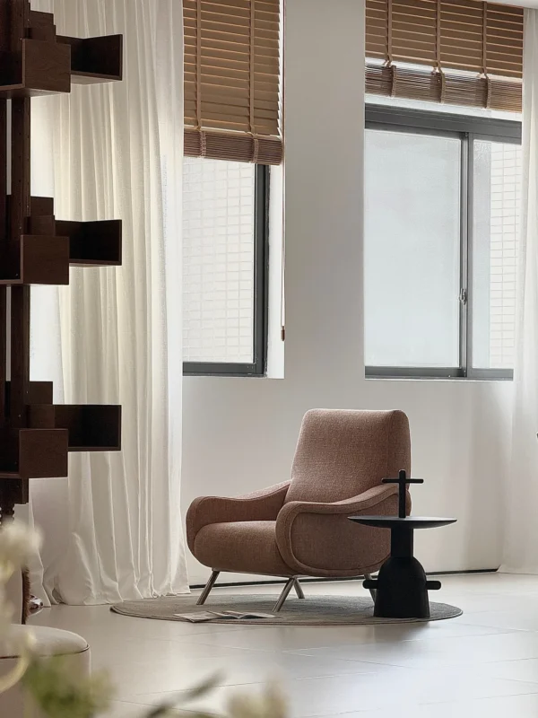 Curved Blush Fabric Lounge Chair on Slim Metal Legs in rose stone — in a room setting