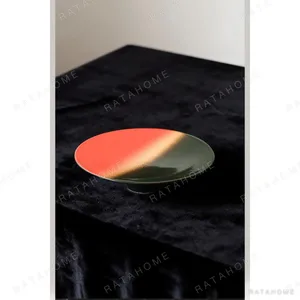 Kiln-Glaze Footed Dessert Plate in Red, Green and Sand Gold — in a room setting