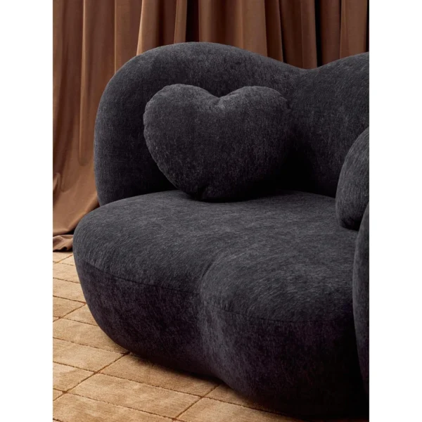 Nian Black Bouclé Curved Armchair with Heart Cushion in black — in a room setting