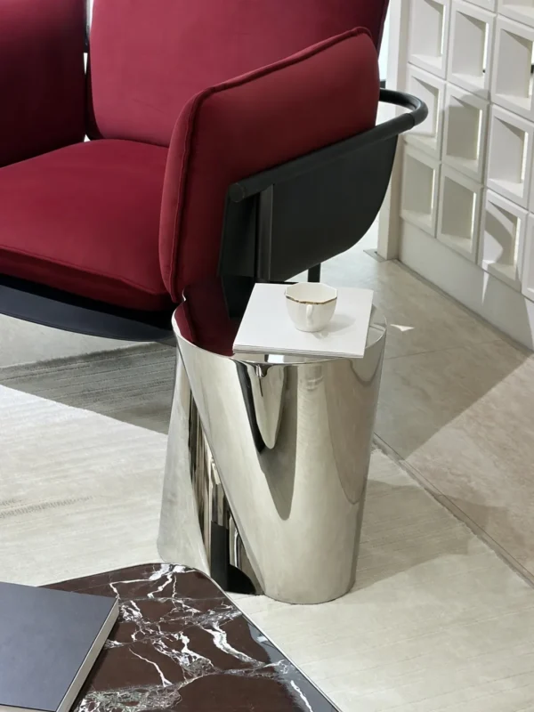 Twisted Cylinder Mirror Steel Side Table in silver — in a room setting