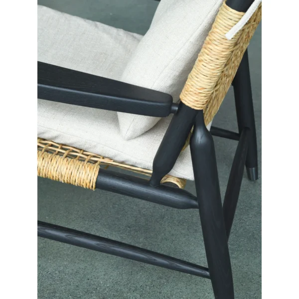Black Oak Lounge Chair with Rattan Seat and Down Cushion in black — in a room setting