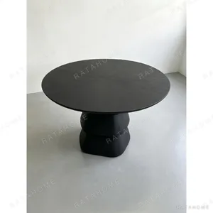 Black Oak Round Table on Stacked Sculptural Pedestal in black — in a room setting