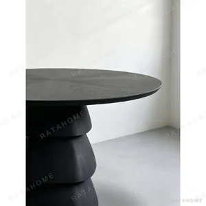 Black Oak Round Table on Stacked Sculptural Pedestal in black — in a room setting