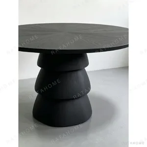 Black Oak Round Table on Stacked Sculptural Pedestal in black — in a room setting