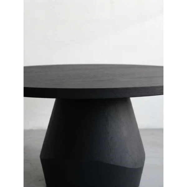 Matte Black Oak Round Dining Table on Faceted Pedestal in black — in a room setting