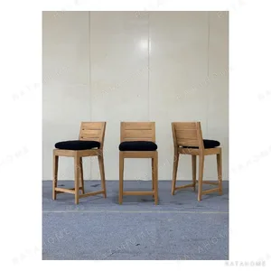 Outdoor Teak Bar Stool with Slatted Back and Black Cushion in natural oak — in a room setting