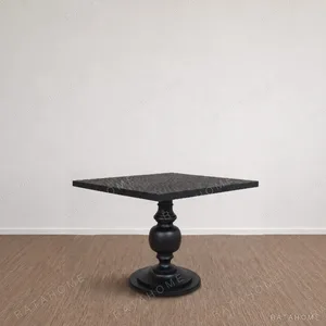 Inkstone Solid Wood Pedestal Table with Turned Old Wood Base in black — in a room setting
