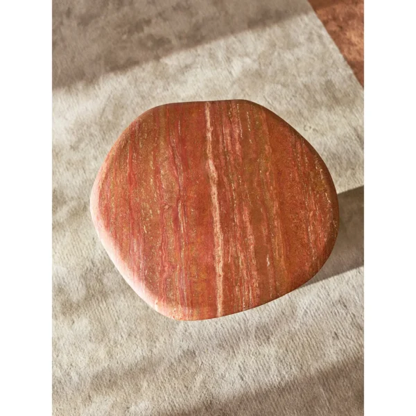 Red Travertine Pebble Side Table on Black Cylinder Base in red — in a room setting
