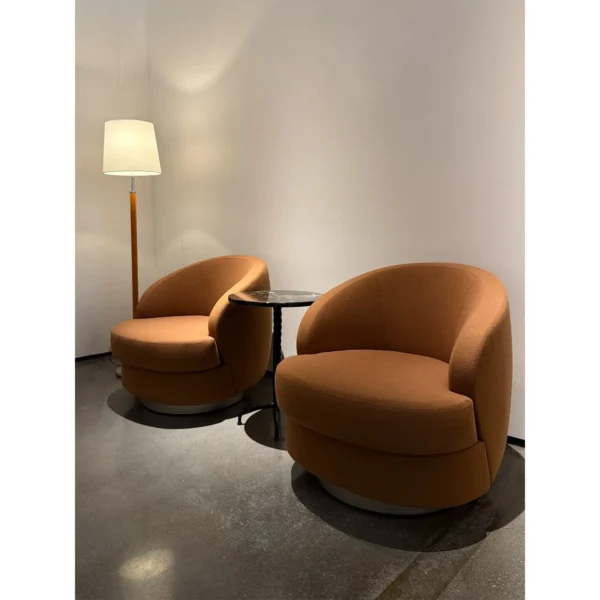 Curved Caramel Fabric Swivel Lounge Chair on Slim Base in rust — in a room setting