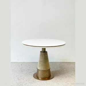 White Stone Round Table on Textured Brass Cone Base in ivory — in a room setting