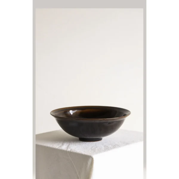 Artist Collaboration Black Glaze Conical Bowl in black — in a room setting