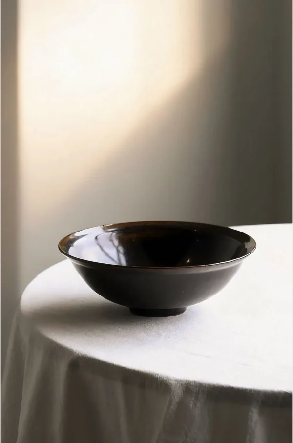 Artist Collaboration Black Glaze Conical Bowl in black — in a room setting