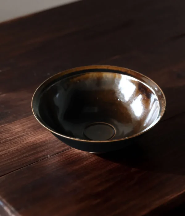 Artist Collaboration Black Glaze Conical Bowl in black — in a room setting