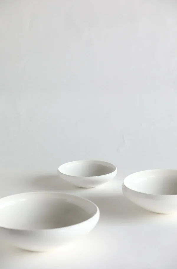 Artist Collaboration Rolled-Edge White Ceramic Bowls, Three in ivory — in a room setting
