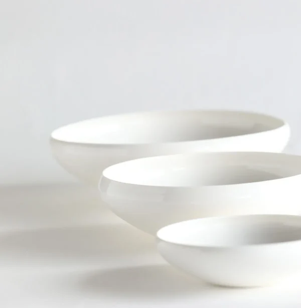 Artist Collaboration Rolled-Edge White Ceramic Bowls, Three in ivory — in a room setting