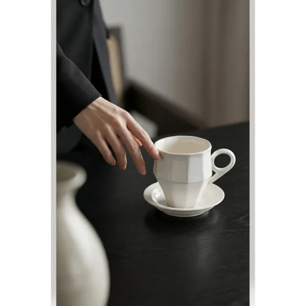 Artist Collaboration Faceted White Ceramic Coffee Mug in ivory — in a room setting