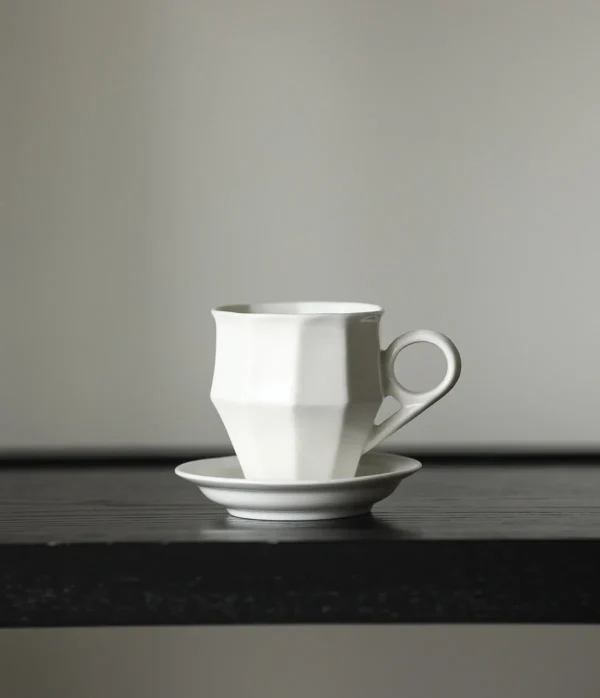 Artist Collaboration Faceted White Ceramic Coffee Mug in ivory — in a room setting