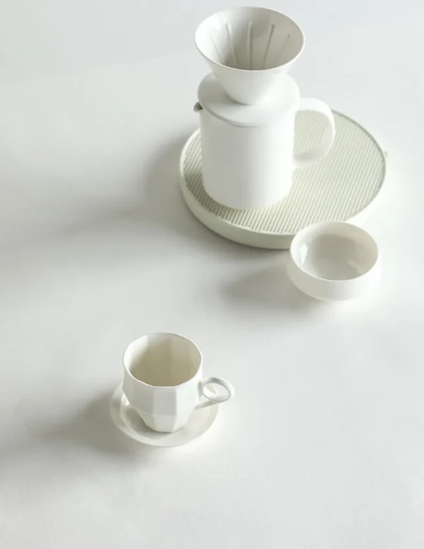 Artist Collaboration Faceted White Ceramic Coffee Mug in ivory — in a room setting