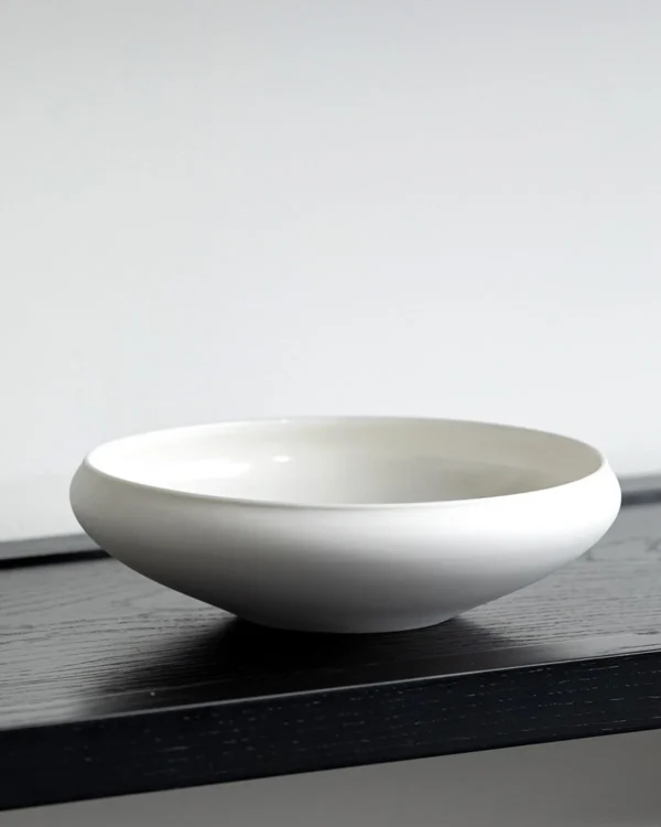 Artist Collaboration Plain Flat Round Shallow Bowl, Small in ivory — in a room setting