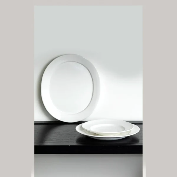 Artist Collaboration Plain Wide-Rim White Flat Plates in ivory — in a room setting