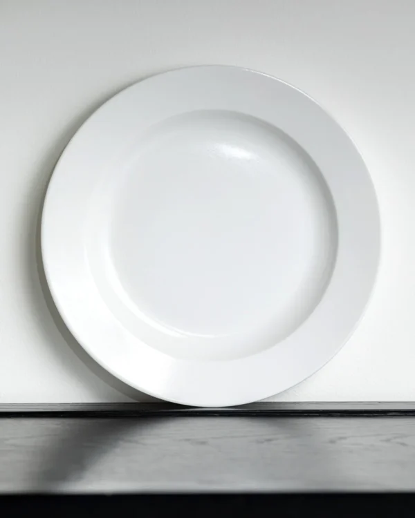 Artist Collaboration Plain Wide-Rim White Flat Plates in ivory — in a room setting
