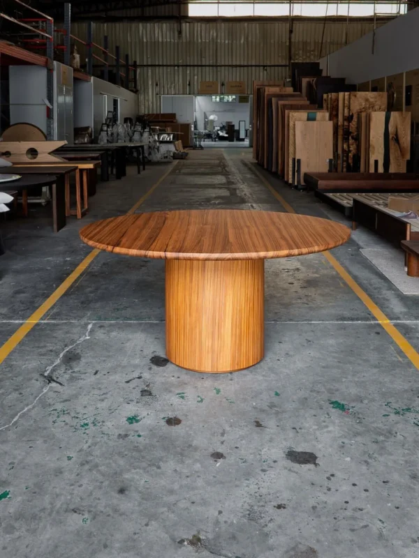 Burmese Teak Round Dining Table on Fluted Drum Base in natural oak — in a room setting