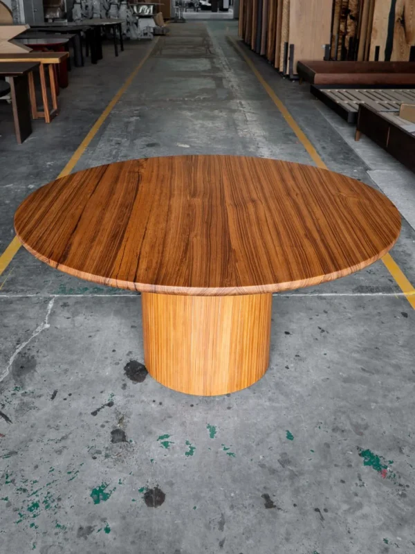 Burmese Teak Round Dining Table on Fluted Drum Base in natural oak — in a room setting