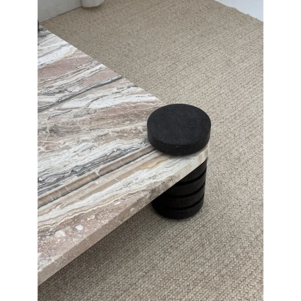 Square Travertine Coffee Table on Stacked Black Stone Legs in sand — in a room setting
