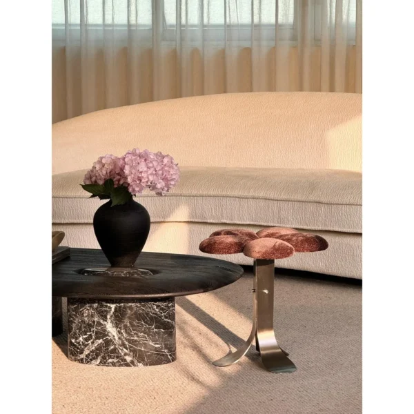 Petal Upholstered Stool on Curved Stainless-Steel Base in rose stone — in a room setting