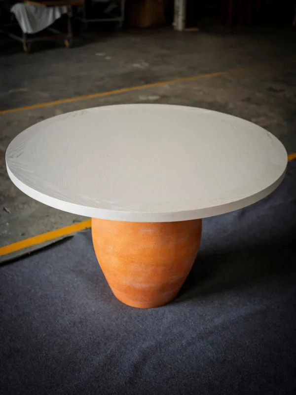 Terracotta Urn-Base Round Dining Table in rust — in a room setting