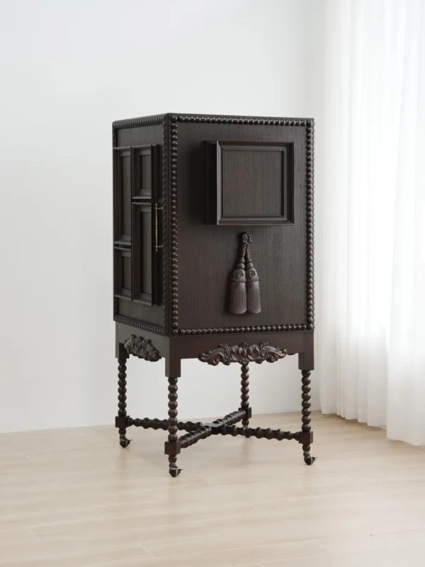 Carved Sequence Cabinet on Barley-Twist Legs with Tassels in black — in a room setting