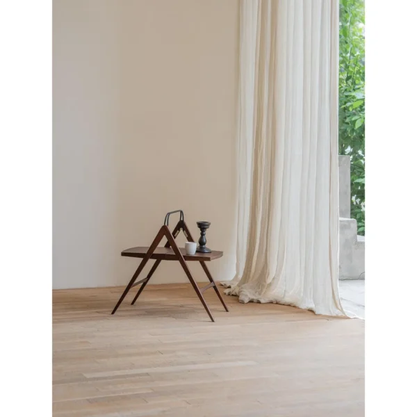 Yuban Folding Wood Side Table with Black Metal Handle in walnut — in a room setting