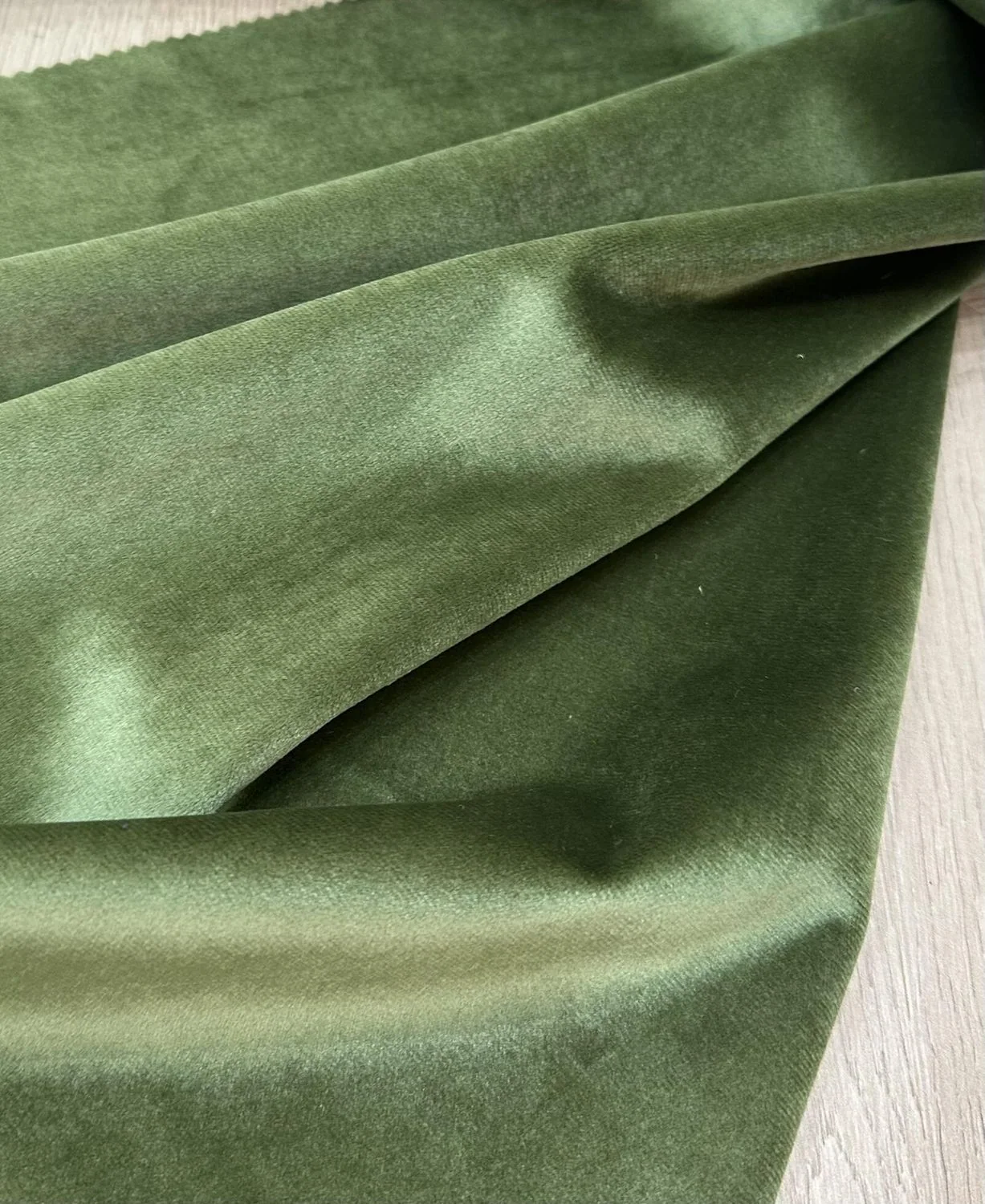 Green velvet fabric folded to show pile direction