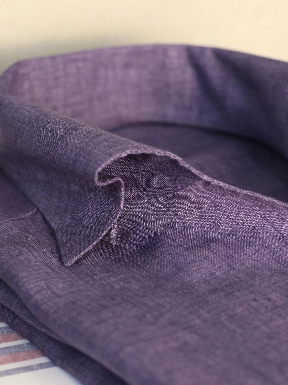 Purple linen textile showing a raw edge and weave