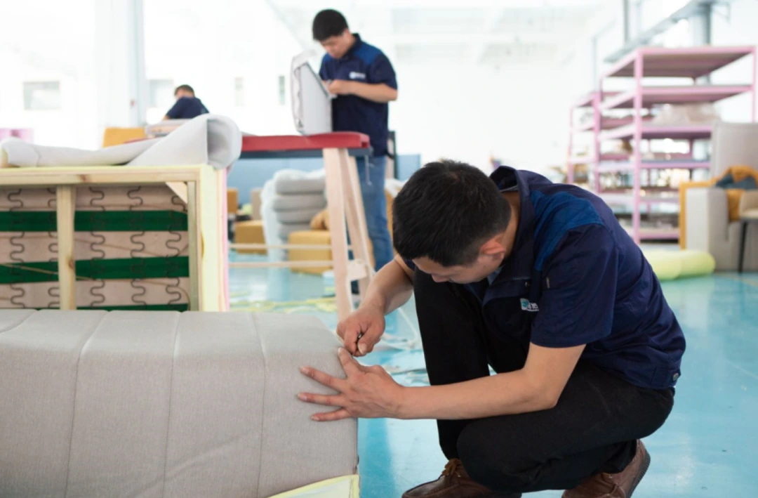 Factory worker checking sofa upholstery by hand
