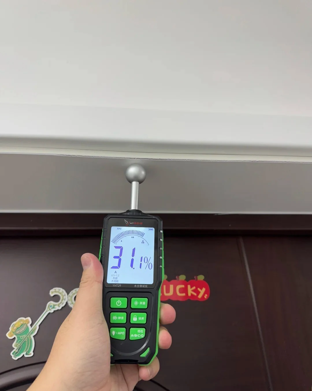 Real handheld moisture meter taking a reading on wood