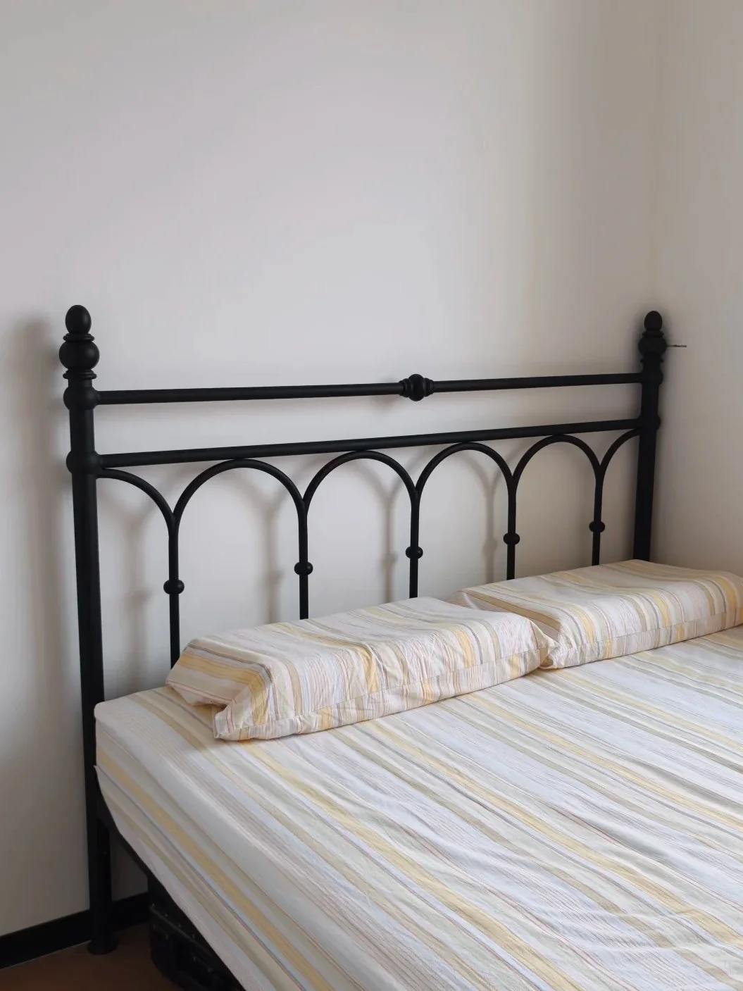 A black iron bed shows how a thin structural frame can become the visual identity of the furniture.