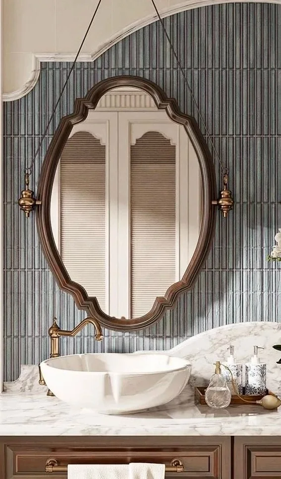 Brass mirror details add warmth beside stone and wood without overwhelming the room.