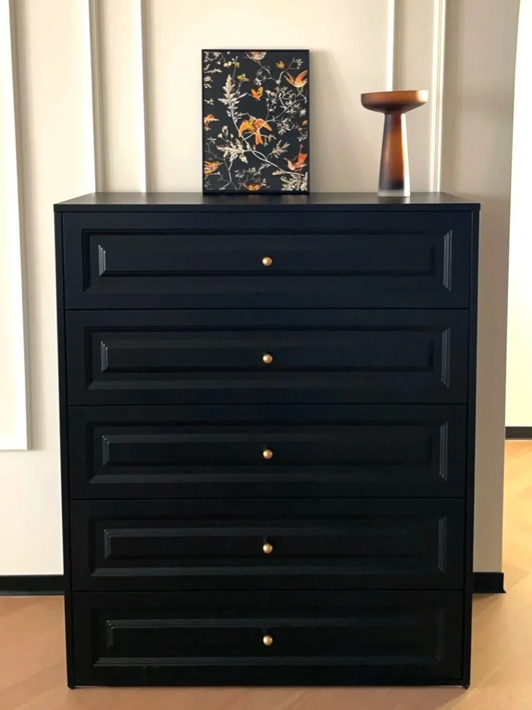 A dark metal finish can become a repeating anchor color for casegoods and frames.