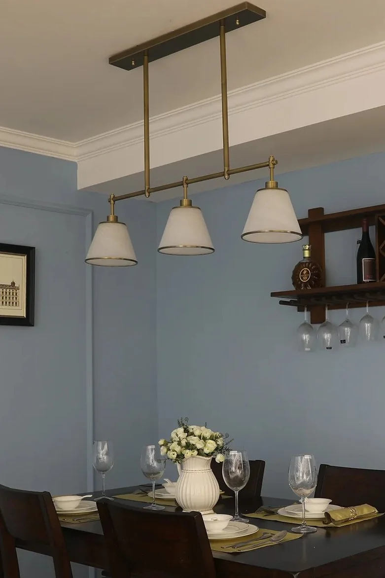 Warm brass lighting can be reserved as the accent finish that ties dining, living and hardware together.
